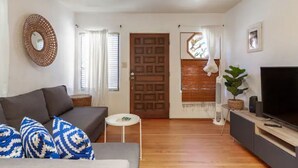 Un salon avec un canapé, un téléviseur, une petite table et une porte.