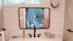 Une salle de bain avec un lavabo en marbre, un grand miroir et une fenêtre au-dessus du lavabo.