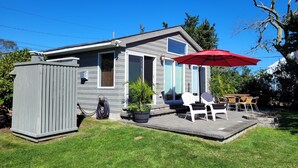 Une maison de plain-pied dotée d’un patio aménagé avec du mobilier d’extérieur et un parasol rouge.