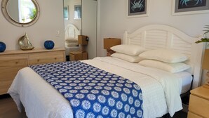 Une chambre à coucher avec un lit, une commode, un miroir et un tableau encadré accroché au mur.