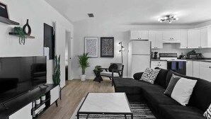 A modern living room with a black sofa, a white coffee table, and a flat-screen TV.