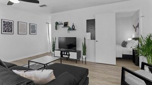 A modern living room with a sofa, coffee table, TV, and plants.