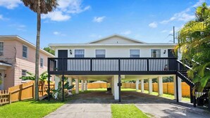 A two-story house with a balcony, a covered driveway, and a fenced backyard.