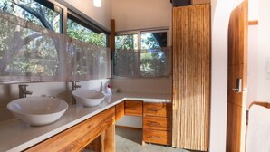 Uma casa de banho moderna com duas pias espaçosas, armários de madeira e uma janela grande que permite entrada de luz natural.
