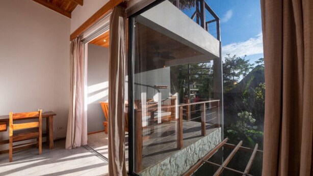 Quarto moderno com uma grande janela de vidro, mobiliário de madeira e vista para uma paisagem montanhosa.