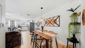 A modern kitchen with a dining area, wooden flooring, and a hanging pendant light.