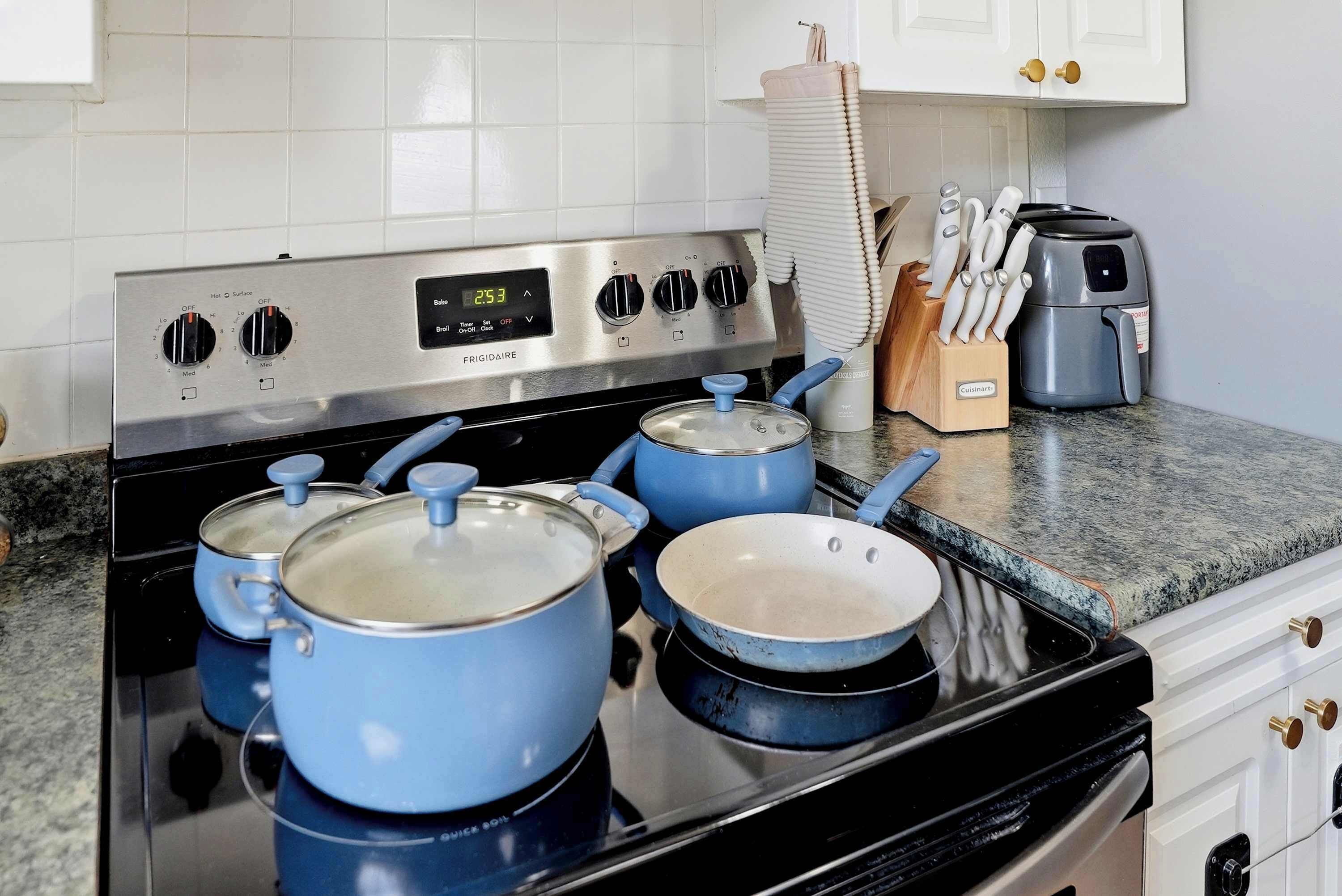 A kitchen with a stainless steel stove, blue pots, a toaster, and a knife block.