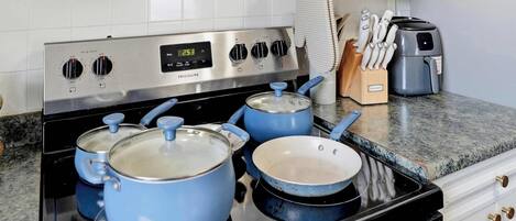 A kitchen with a stainless steel stove, blue pots, a toaster, and a knife block.