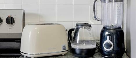 A kitchen with a white toaster, a black blender, and a clear glass pitcher on a granite countertop.