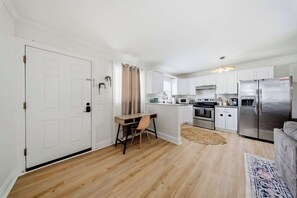A compact kitchen with white cabinets, a wooden dining table, and a modern refrigerator.