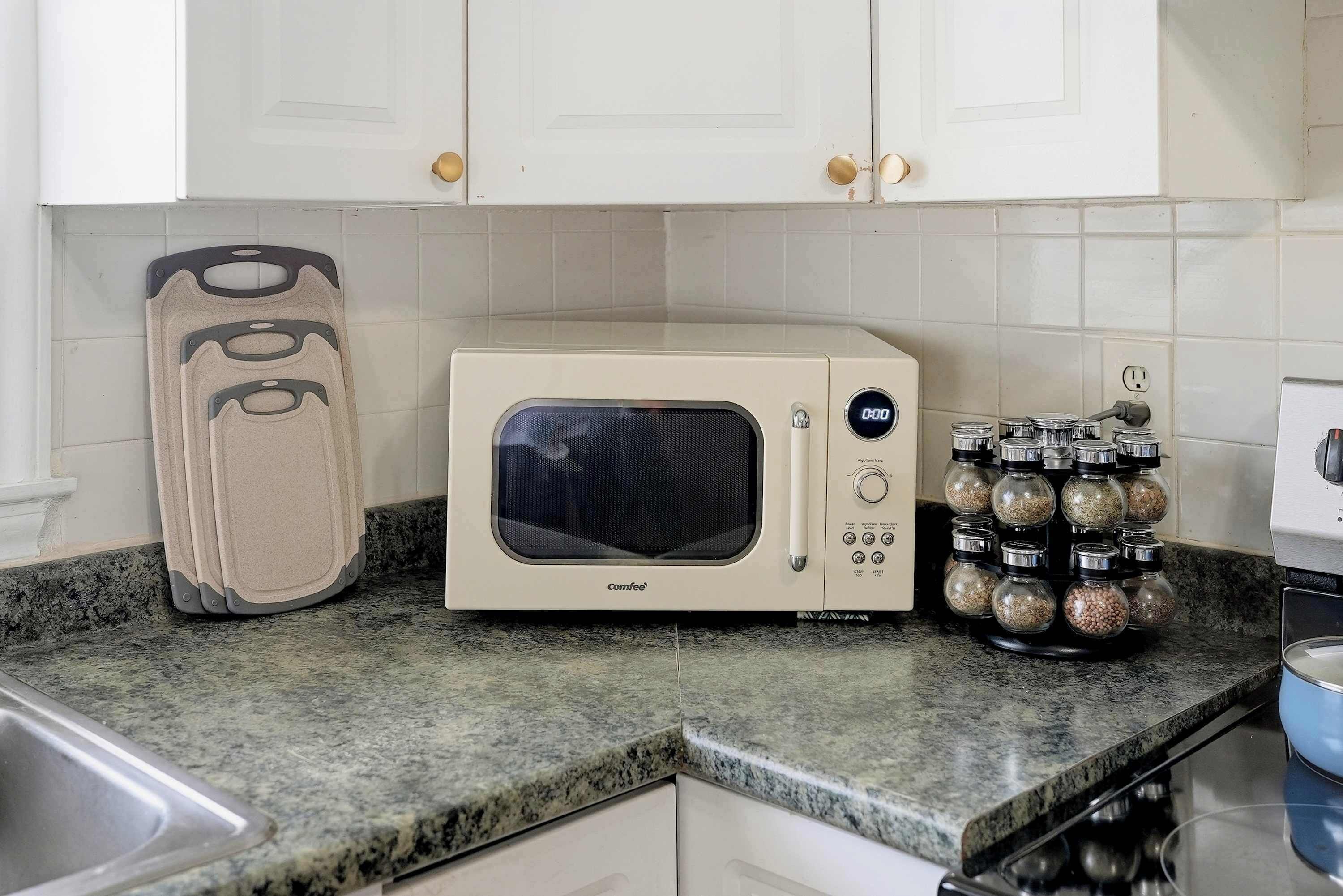 A kitchen with a microwave, a spice rack, and a countertop.