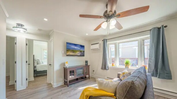 A living room with a ceiling fan, a sofa, a TV, and a window with curtains. - Modern Seaside Condo, 2 Blocks to Sand+ Parking - a Seaside Heights Sanctuary! (Seaside Heights)