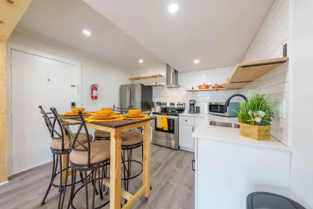 Een moderne keuken met een eettafel, stoelen en diverse apparaten.