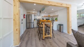 A modern kitchen with wooden beams, a stainless steel refrigerator, and a dining area with a table and chairs. - Modern Seaside Condo, 2 Blocks to Sand+ Parking - a Seaside Heights Sanctuary! (Seaside Heights)