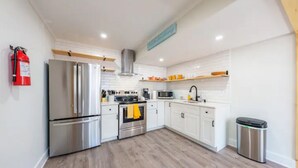 A modern kitchen with white cabinets, stainless steel appliances, and a wooden floor. - Modern Seaside Condo, 2 Blocks to Sand+ Parking - a Seaside Heights Sanctuary! (Seaside Heights)