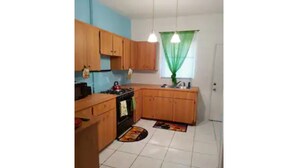 Una cocina compacta con armarios de madera, una estufa y un lavabo.