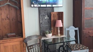 A room with a wooden cabinet, a table with a glass top, two chairs, a television, and a lamp.