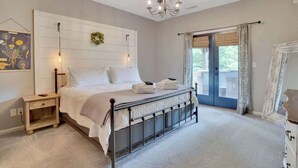 Un dormitorio con cama, mesita de noche, candelabro y vistas al exterior.