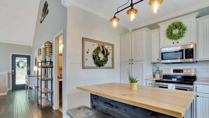 Una cocina con gabinetes blancos, una isla de madera, un microondas y un horno de acero inoxidable.