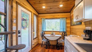 A compact kitchen with a dining table, chairs, and a coffee maker.