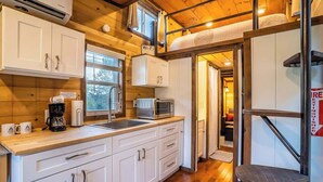 A compact kitchen with white cabinets, a microwave, a coffee maker, and a Wi-Fi sign.