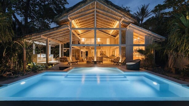Ein modernes Haus mit Swimmingpool, großen Fenstern und einer überdachten Terrasse.