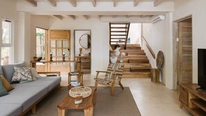 Ein großzügiger Wohnbereich mit Sofa, Holzmöbeln, einer Treppe und einem Fernseher.