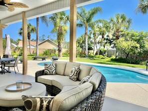 A covered outdoor seating area with a pool, wicker furniture, and a view of palm trees. - Beach 2 Blocks, Private Resort Pool,2GolfCarts, 5Bdrms, Hot Tub,3Baths (Port St. Joe)