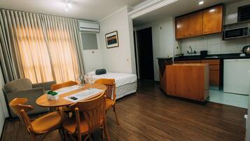 A compact hotel room with a dining area, kitchenette, and a bed.