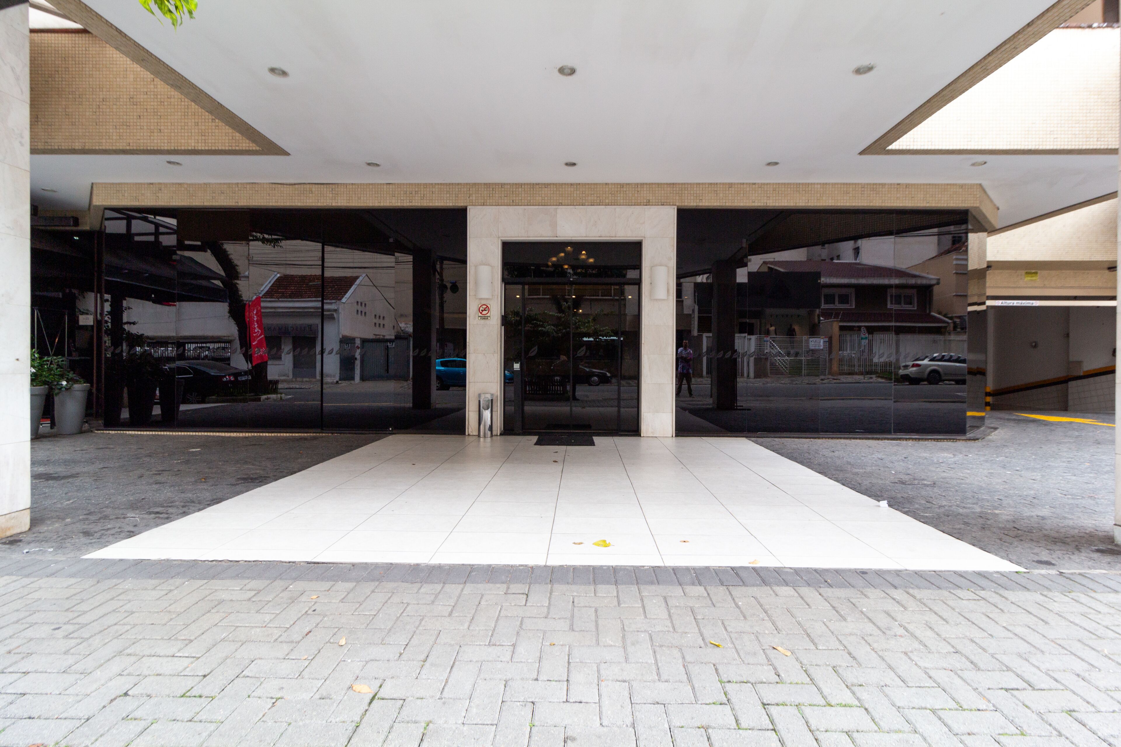 A modern building entrance with a glass facade, a central door, and a tiled floor.