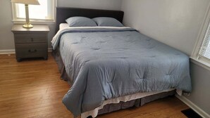 A bedroom with a bed, a nightstand, a lamp, and a window. - Cheerful 2 bedroom home with parking on premises (Indianapolis)