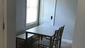 A room with a dining table and chairs, a window with blinds, and a door. - Cheerful 2 bedroom home with parking on premises (Indianapolis)