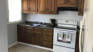 A kitchen with wooden cabinets, a double sink, a stove, and a refrigerator. - Cheerful 2 bedroom home with parking on premises (Indianapolis)