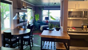 A modern kitchen with a dining area, large windows, and a view of the street. - Avalon Guesthouse : Eastside Suite (Grand Marais)
