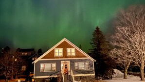 A house with a front porch and a snow-covered yard. - Avalon Guesthouse : Eastside Suite (Grand Marais)