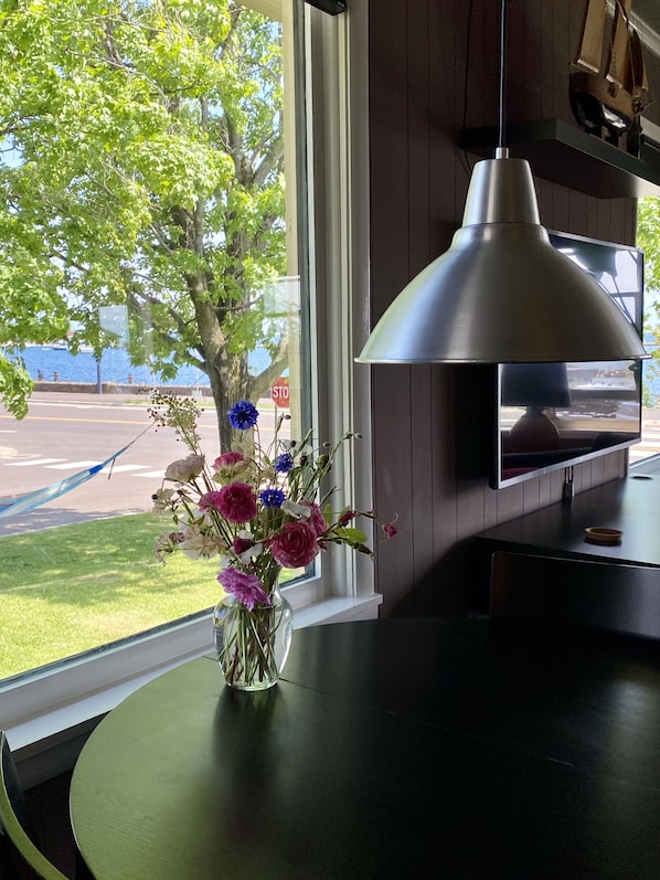 A modern kitchen with a large window, a vase of flowers, and a hanging pendant light.