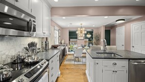 A modern kitchen with stainless steel appliances, a central island, and a dining area with a chandelier. - Beautiful 3-Bdrm Home <> Park 2 Cars <> King Bed (Alexandria)