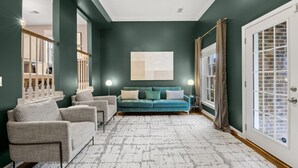 A living room with a teal sofa, grey armchairs, and a white patterned rug. - Beautiful 3-Bdrm Home <> Park 2 Cars <> King Bed (Alexandria)