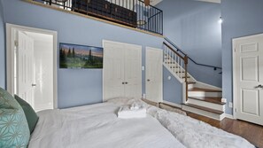 Une chambre à coucher avec un lit, un escalier et un tableau accroché au mur.