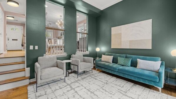 Un salon moderne avec un canapé de couleur turquoise, deux fauteuils et une table basse.