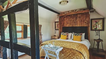 A bedroom with a wooden headboard, a bed with yellow and white bedding, a small table with a teapot, and a window with curtains.