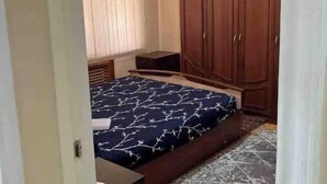 A bedroom with a bed, a wardrobe, a bedside table, and a patterned floor. - Lovely 2-bedroom apartment with free parking. (Тошкент)