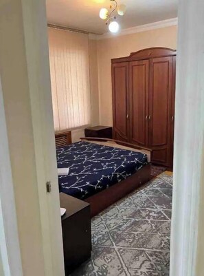 A bedroom with a bed, a wardrobe, a bedside table, and a patterned floor. - Lovely 2-bedroom apartment with free parking. (Тошкент)