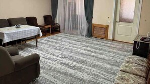 A living room with a dining table, two armchairs, a sofa, a chandelier, a clock, and a door with a frosted glass panel. - Lovely 2-bedroom apartment with free parking. (Тошкент)