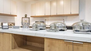 Une cuisine moderne avec des comptoirs en marbre, des armoires en bois et des couvercles en verre sur le plan de travail central (l’îlot).