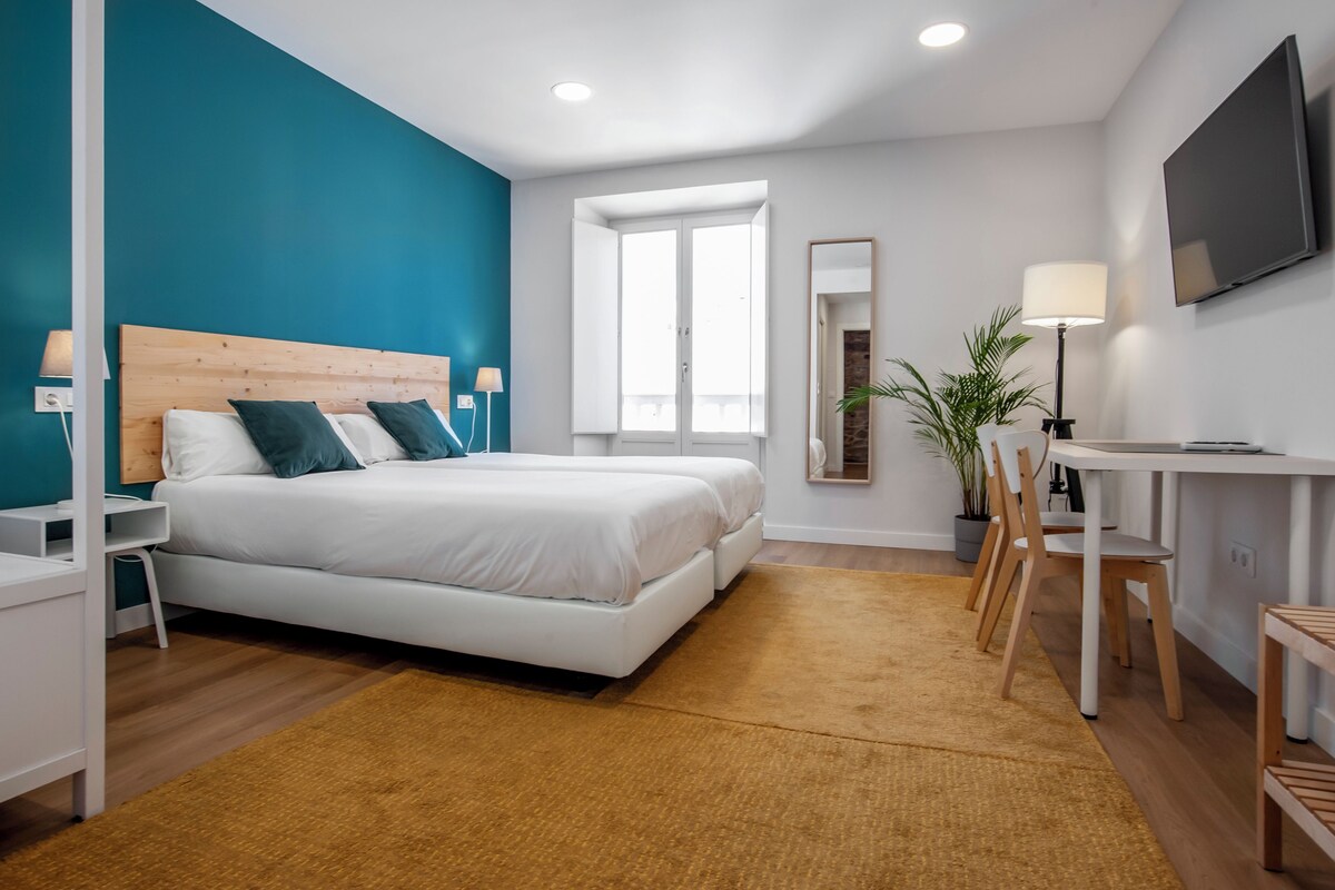 Un dormitorio moderno con cama, mesitas de noche, un escritorio y una silla.