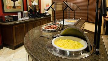 A buffet setup with various food items and a coffee station.