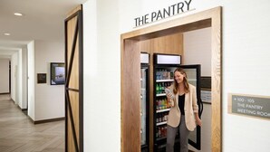 Un corridoio con un cartello che indica 'THE PANTRY' e un frigorifero pieno di bevande.