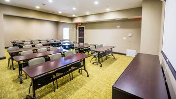 A conference room with multiple tables and chairs, carpeted flooring, and recessed ceiling lights.