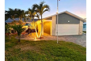 A residential property with a garage, a patio with outdoor furniture, and palm trees. - Coastal Coconut Cove near Anna Maria Island (Bradenton)
